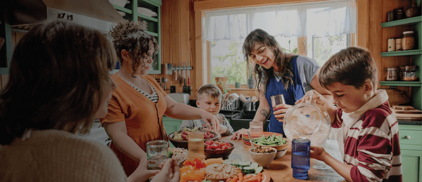 A photo of a happy family gathered around their table, each with a glass of clean tap water in hand or nearby.